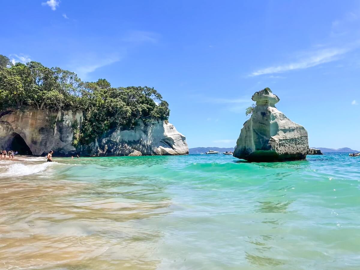 A tourist walks into the water at Cathedral Cove