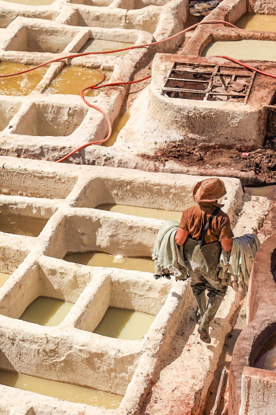 A man walks through the Chouara Tannery holding hides in the Fes Medina - on a guided walking tour
