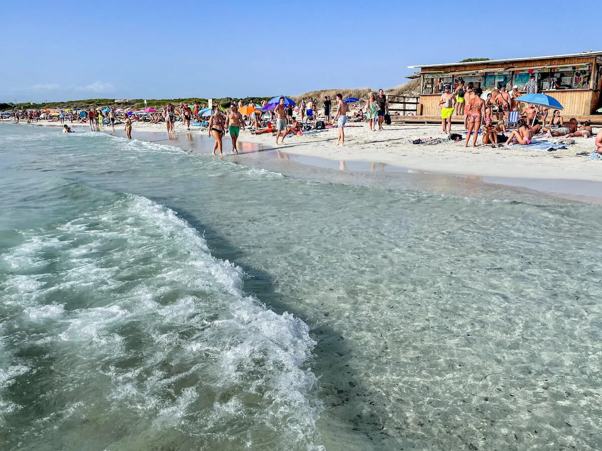 People walk along Platja des Trenc beach in Mallorca in the middle of summer.