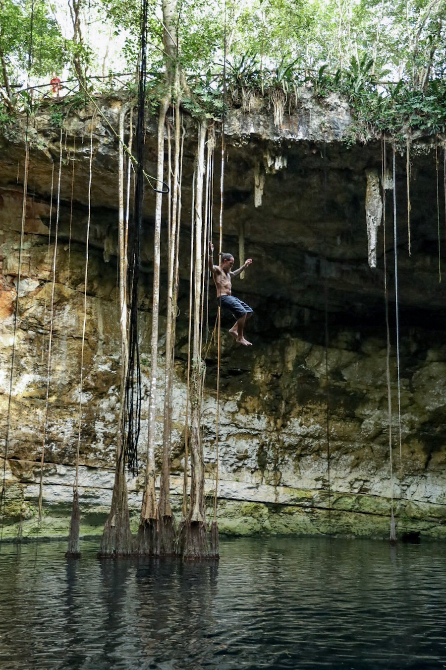 A man jumps from a swing rope at Cenote Secreto Maya - which is one of the hidden gem cenotes in Valladolid