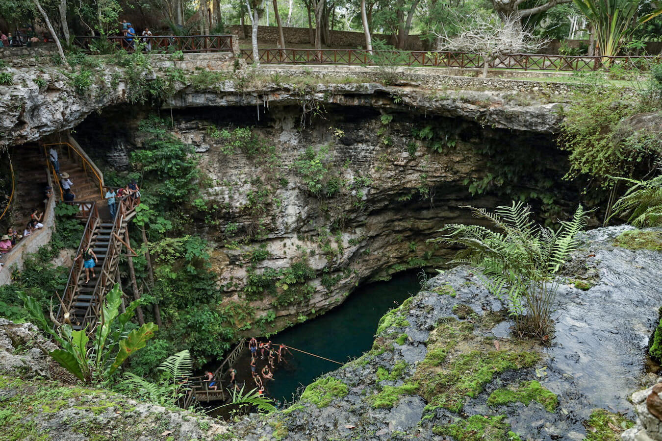A view from above one of the cenotes closest to Valladolid - tourists are seen entering - Cenote Saamal.