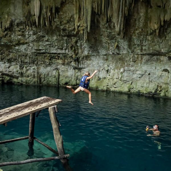 A child jumps from a platform into one of the best Valladolid cenotes