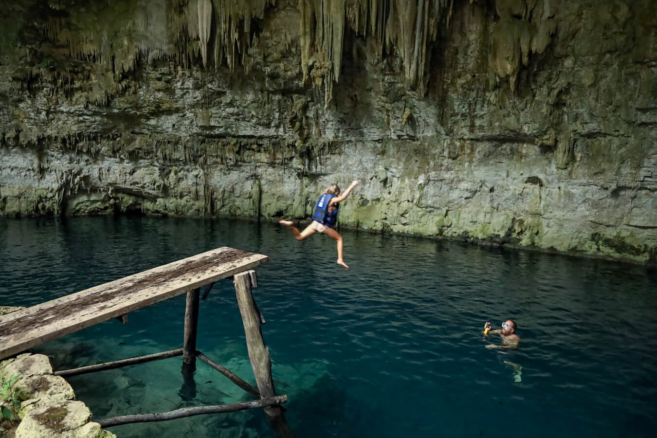 A child jumps from a platform into one of the best Valladolid cenotes