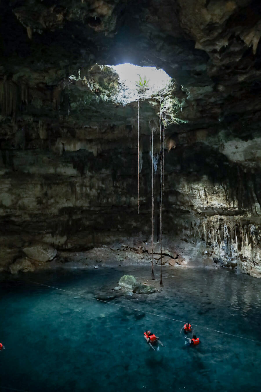 A family swim past under the opening of Cenote Samula in Valladolid - the Dzitnup cenotes are  a great example of closed cenotes.