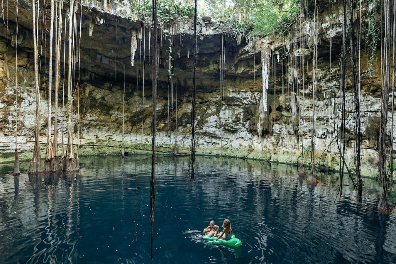A family float on an inflatable crocodile in the middle of Secreto Maya Cenote