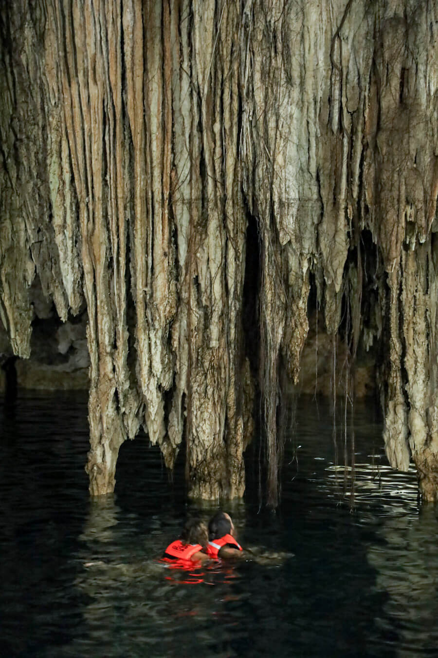 A family swim past incredible stalactites at Cenote Xkeken in Valladolid - the Dzitnup cenotes are  a great example of closed cenotes.