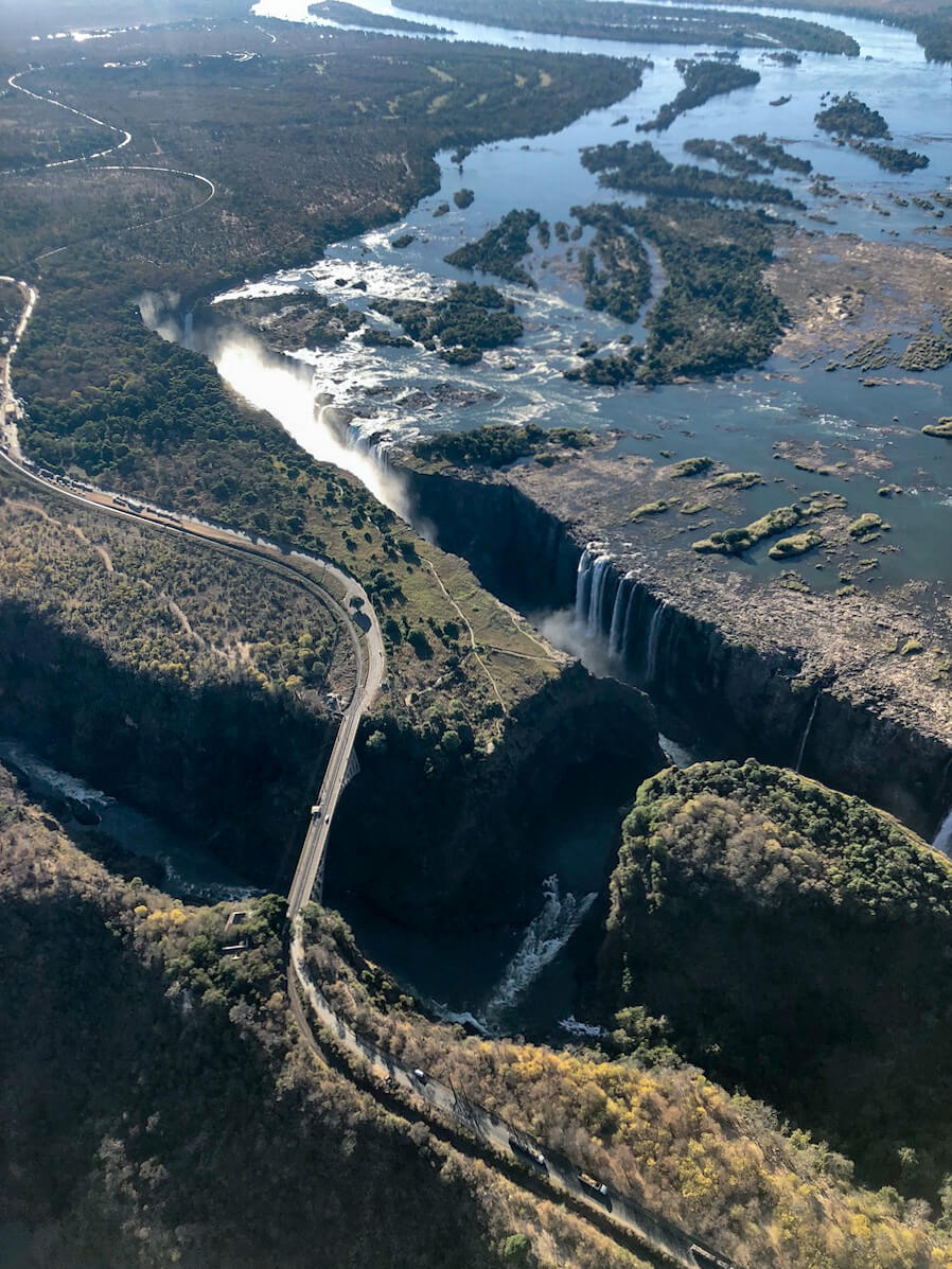 The Zambezi river cascading into the impressive Victoria Falls, and the beautiful Victoria Falls bridge, photographed from a helicopter ride