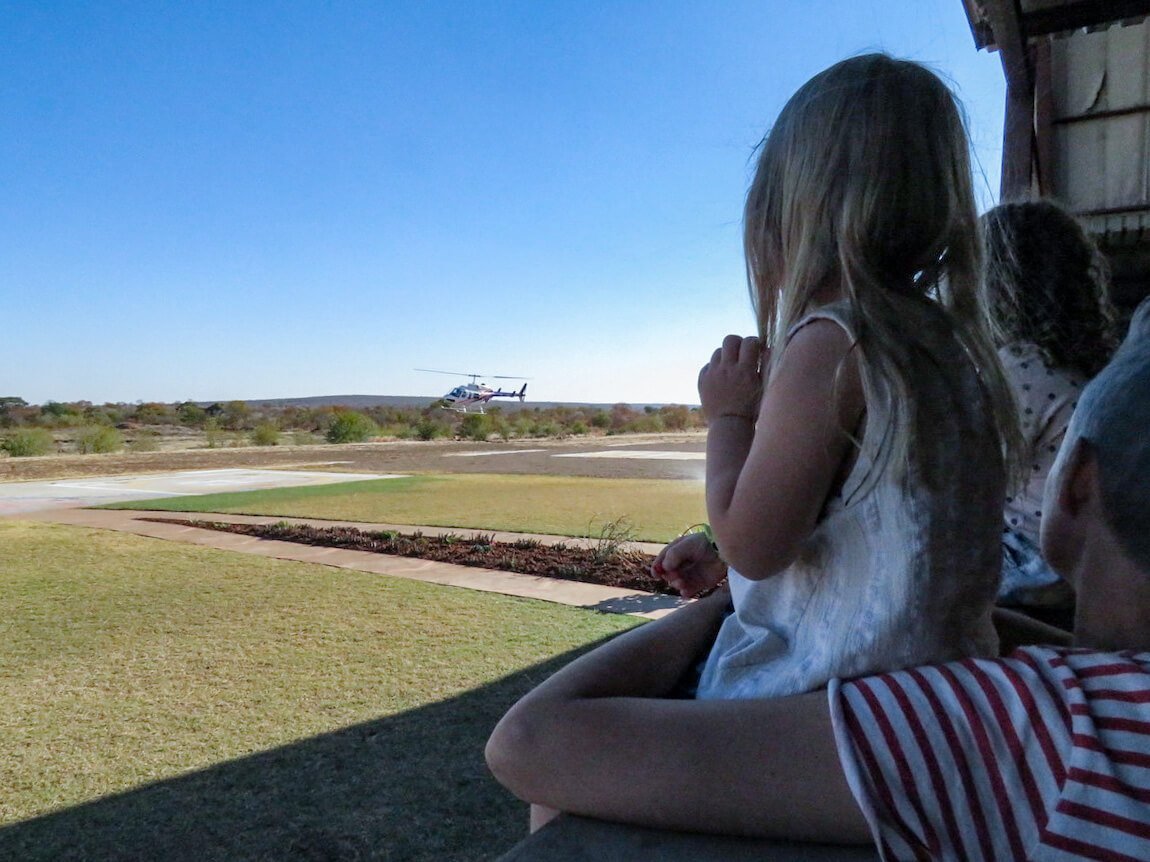 A young child watches a helicopter land on a helipad in Zimbabwe.