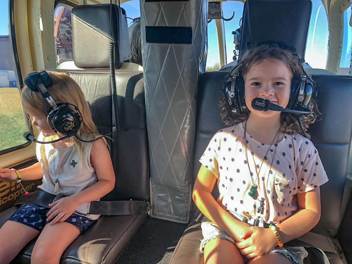 Two young girls sit in a helicopter waiting for the start of a tour.