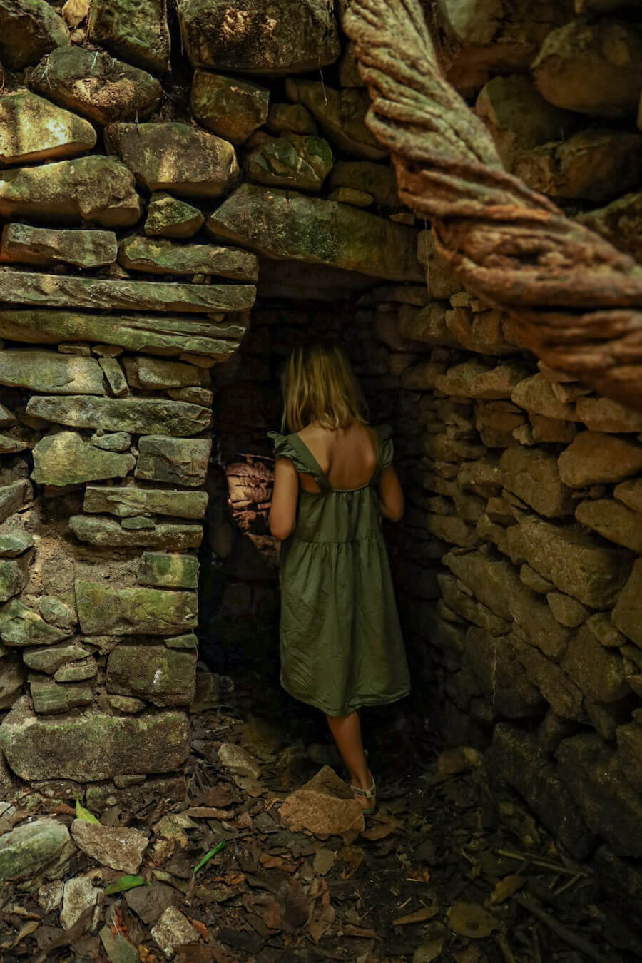 A young girl walks into unexcavated ruins while on a jungle walk with a guide in the Palenque Ruins & National Park 