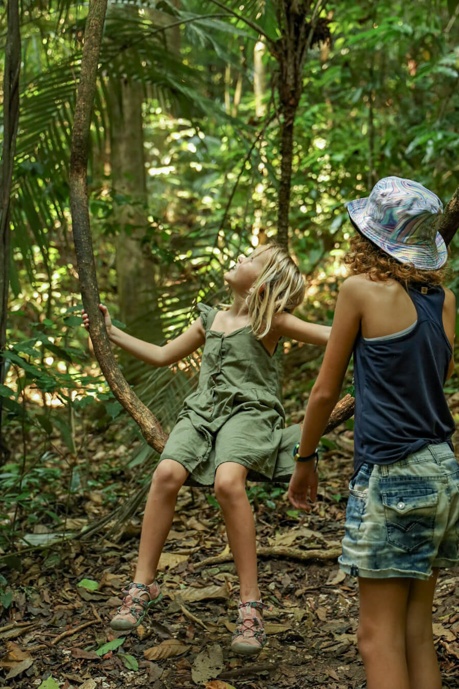 Two girls swinging on a vine while on a jungle walk with a guide in the Palenque Ruins & National Park 