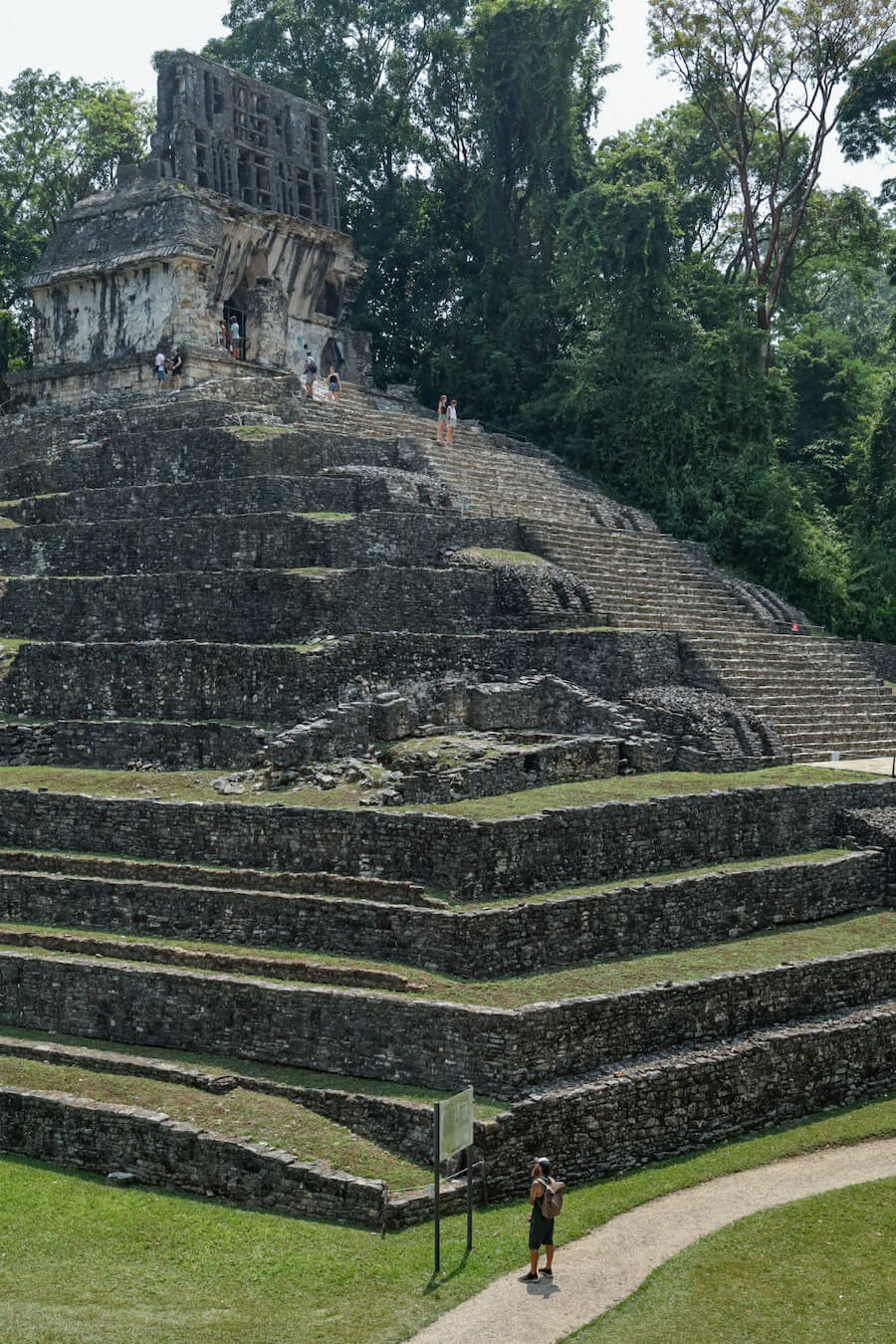 A man standing at the base of the Temple of the Cross reading the sign. Several people standing on top of the Temple of the Cross.