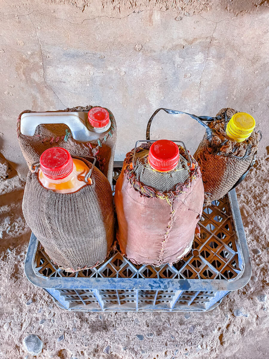 Four plastic drinking water bottles wrapped in damp cloth to keep cool.