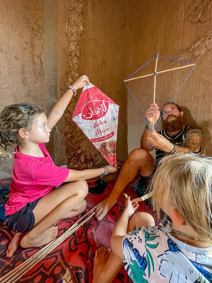 Father and his two daughters making a kite while n a family work exchange in Morocco.