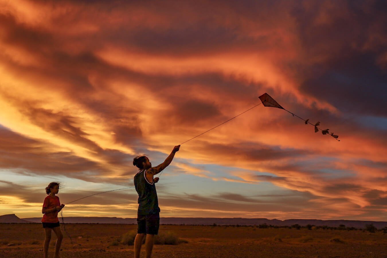 Farther and daughter flying a kite at sunset in the Sahara while on a family work exchange in Morocco.