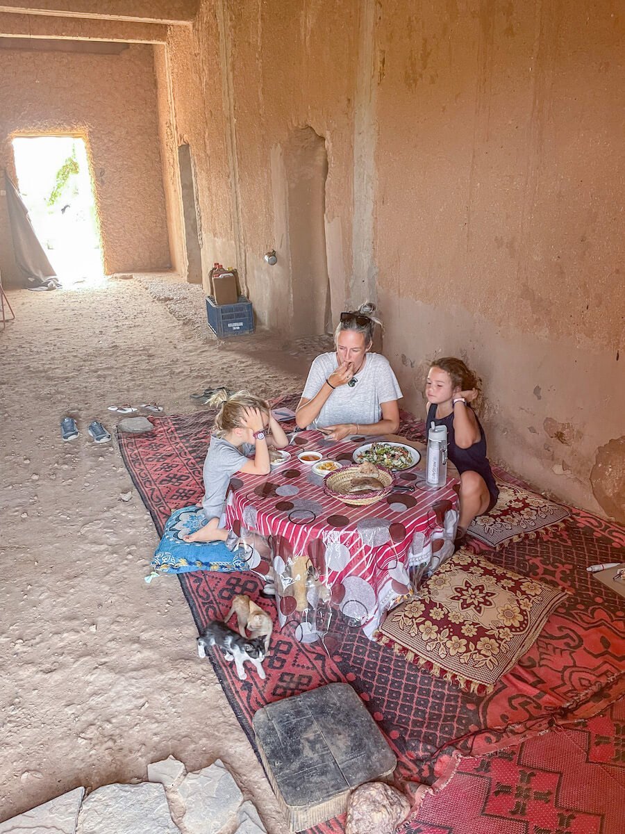 Mother and her two daughters eating lunch in a mud brick house while on a family work exchange in Morocco.