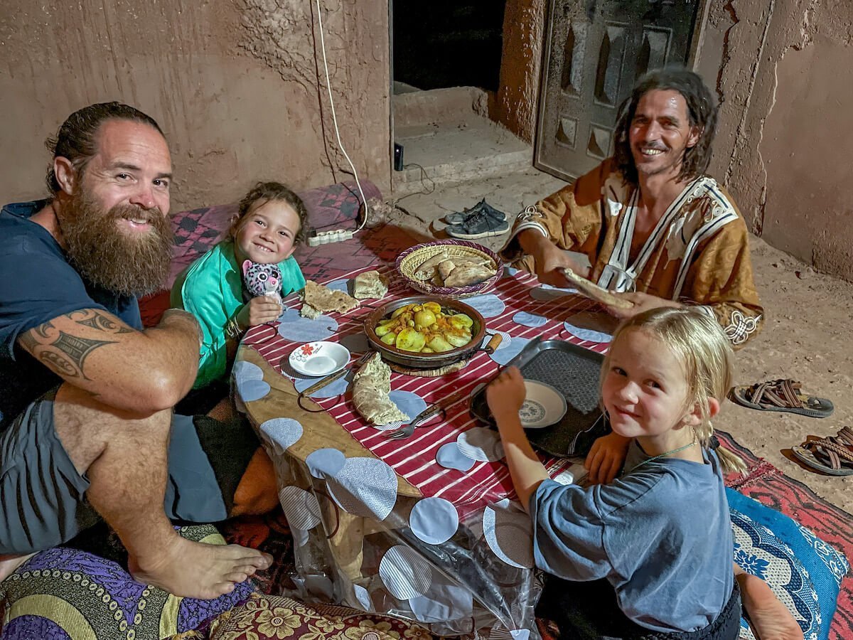Father, his two daughters and their local Berber host sharing dinner during their work exchange in Morocco.