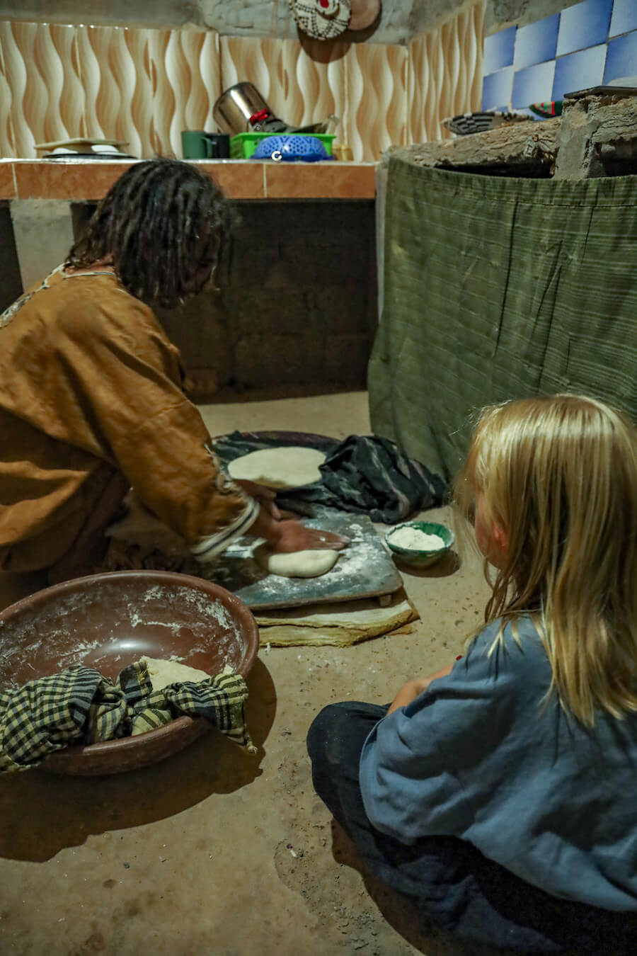 A Berber host showing a young girl how to prepare bread.