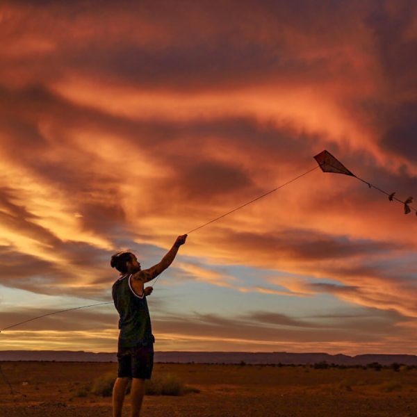 Father and daughter fly a kite at sunset while on a family volunteering and work exchange program.