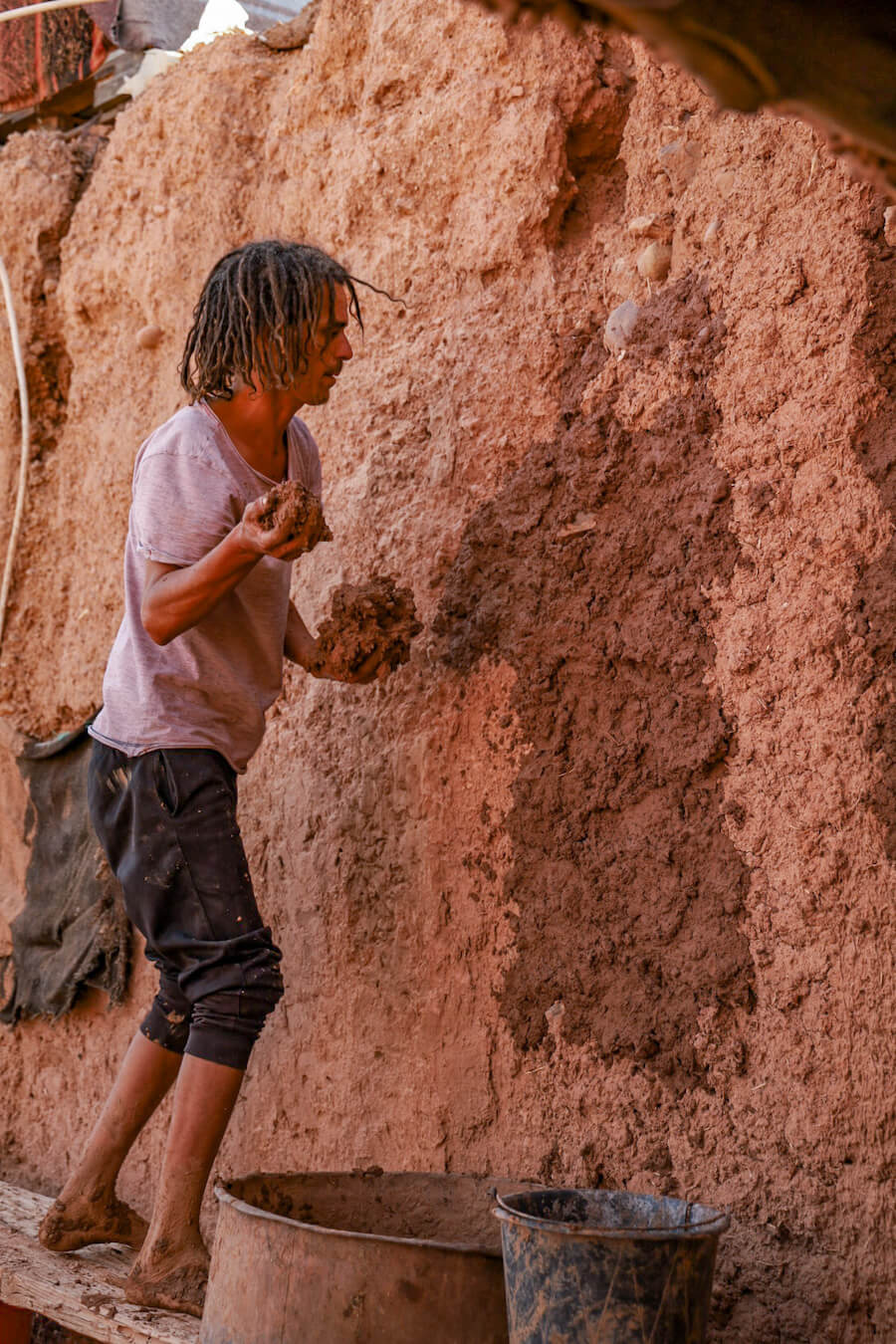 The host on a family work exchange in Morocco applying mud to the exterior walls of his house. 