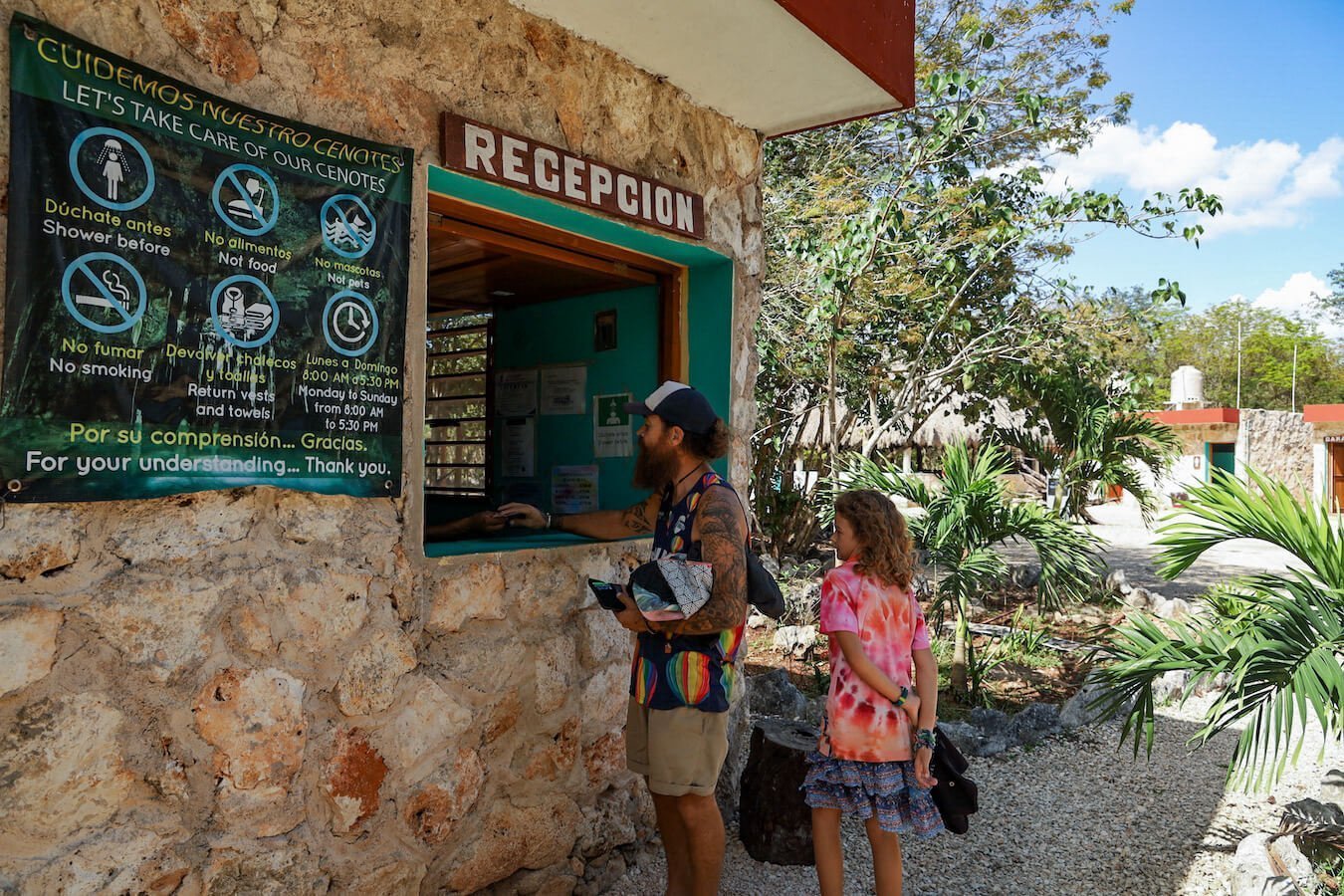 A father and child buy tickets to a cenote in Valladolid.