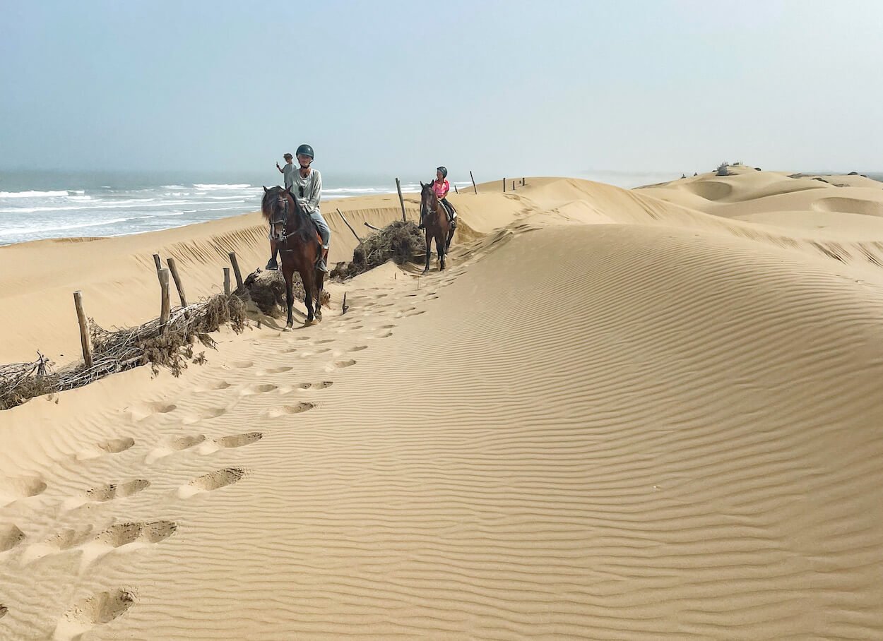 A family on horseback ride through the sand dunes in Essaouira in Morocco