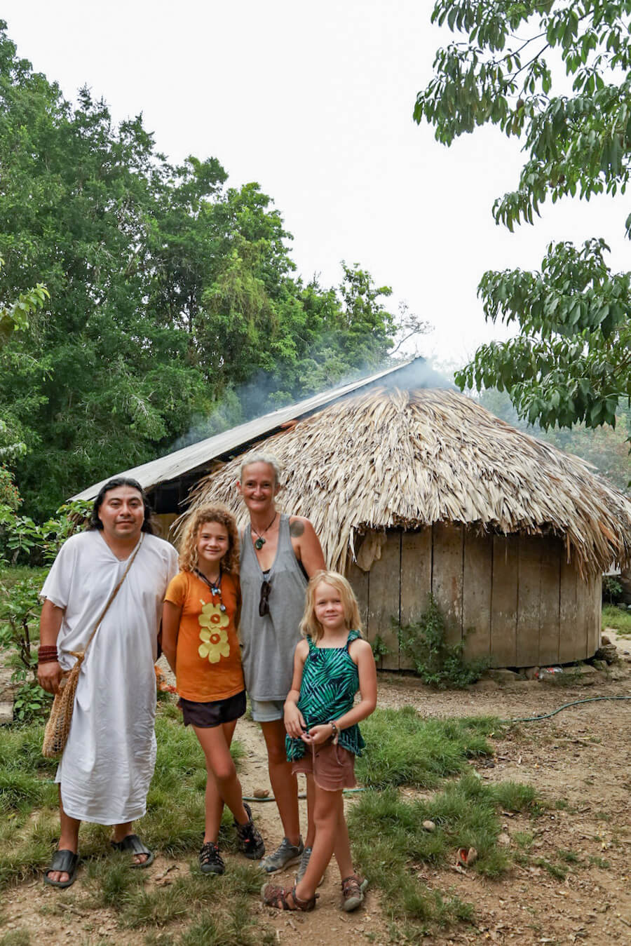 Mother and her two daughters standing with their local guide in front of his house, in the Lacandon rain forest.