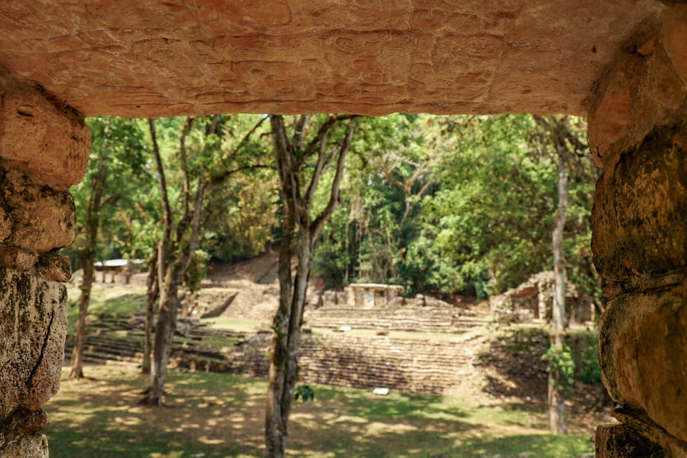 Photo taken from inside ruins, looking out onto the grand plaza and highlighting the decorative lintel, at the top of the door opening.