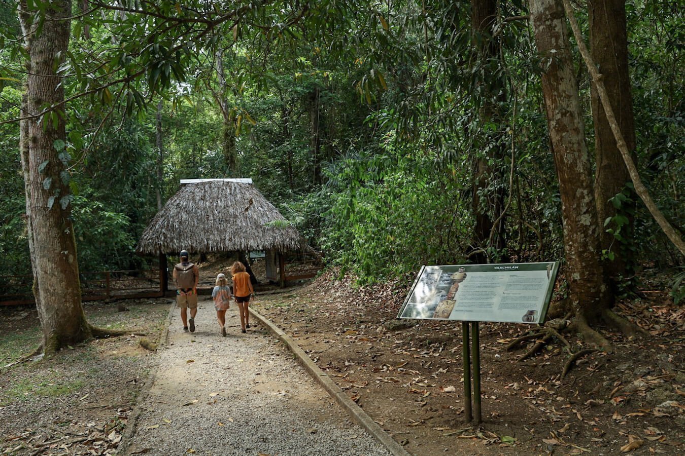 A father and his two daughters walking towards the entrance of Yaxchilán ruins.