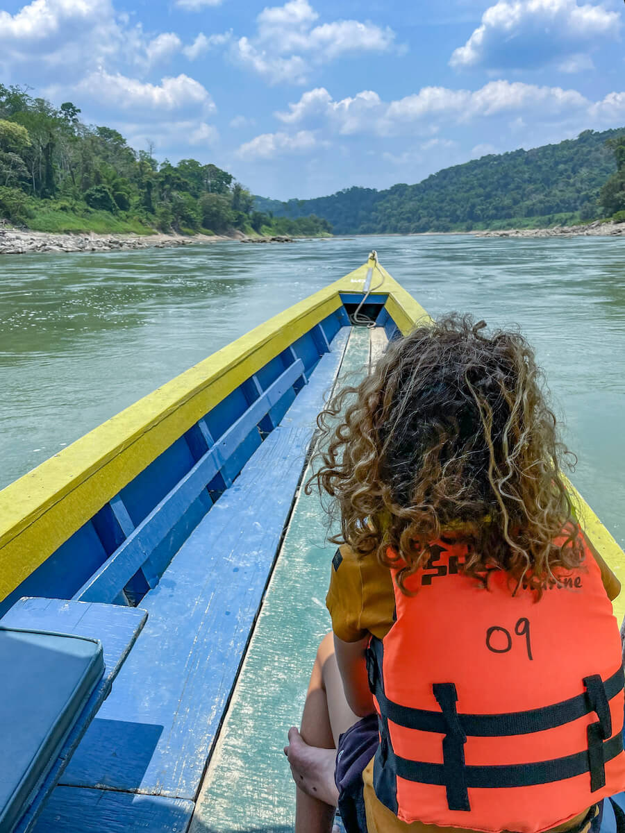 A young girl sitting at the front of a long boat heading down stream to Yaxchilán ruins.